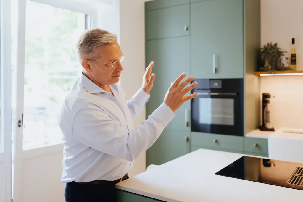 Ulrich Weinkath steht einer Küche einer Klientenwohnung. Er gestikuliert mit beiden Händen.