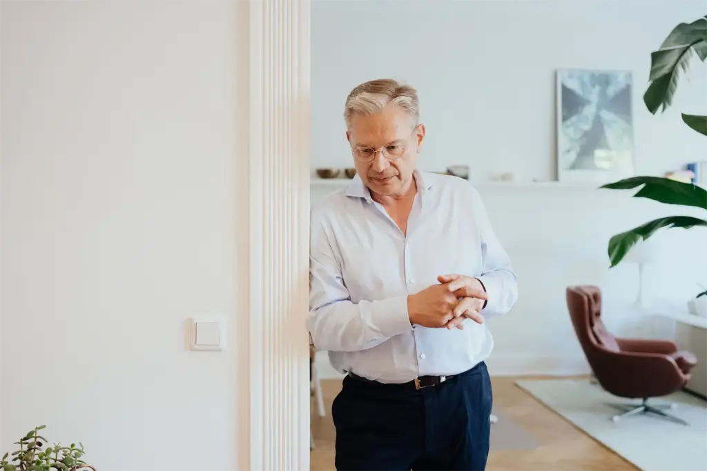 Ulrich Weinkath lehnt am Türrahmen im Durchgang von einer Küche zum Wohnzimmer einer Klientenwohnung.